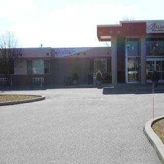 A view of a bank building with a driveway and parking area on a sunny day.
