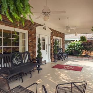 A cozy outdoor patio featuring comfortable seating and lush greenery.