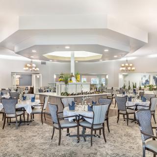 An elegant dining area with neatly arranged tables and chairs, featuring chandeliers and sophisticated decor.