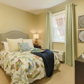 A cozy bedroom with a neatly made bed, soft pillows, and elegant curtains by the window.
