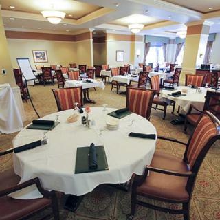 An elegantly set dining room with multiple tables and chairs, ready for guests.