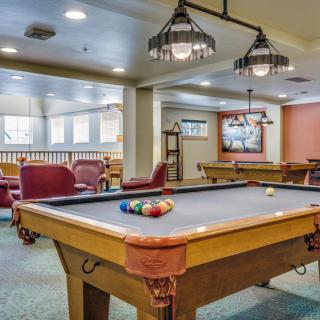 A spacious game room with a billiards table and comfortable seating.