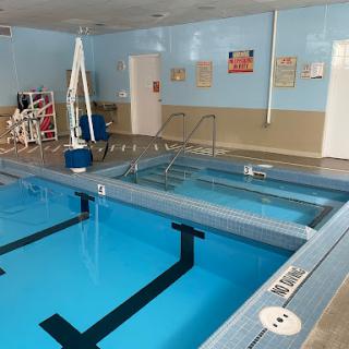 An indoor swimming pool featuring clear blue water and various facilities for accessibility.