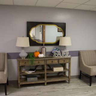 A cozy living room setup featuring a console table with lamps, a decorative mirror, and comfortable seating.