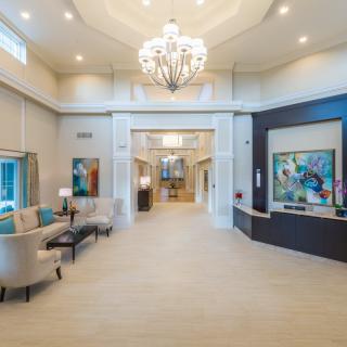 A spacious and elegantly designed lobby featuring a large chandelier, comfortable seating, and modern artwork.