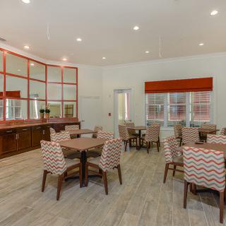 A modern dining area with multiple tables and chairs, featuring large windows and stylish decor.