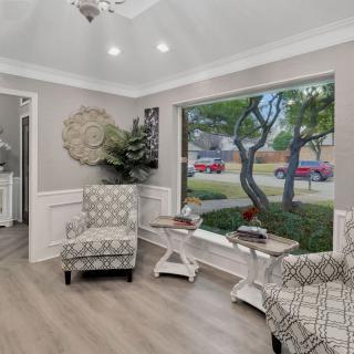 A modern living room with patterned chairs and a large window overlooking the street.