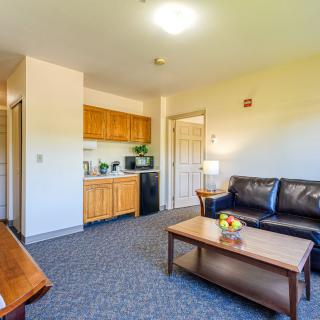 A cozy living room featuring a kitchenette, leather sofa, and coffee table.