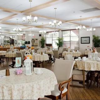 A well-lit dining room with elegantly set tables and chandeliers.