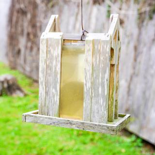 A rustic wooden bird feeder hanging in a garden, inviting feathered friends.