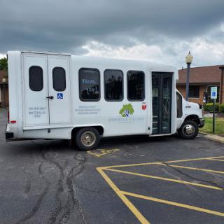 A white accessible bus parked in a lot under a cloudy sky.