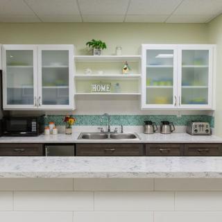 A modern kitchen with glass cabinets, a clean countertop, and appliances like a coffee maker and toaster.