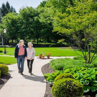 A couple walking together on a pathway through a lush green park.