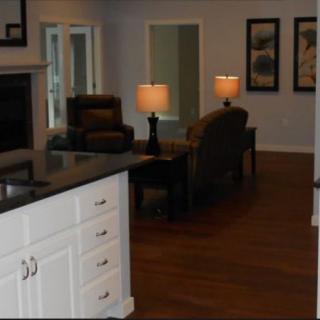A cozy living room with a view of the kitchen counter, featuring comfortable seating and warm lighting.