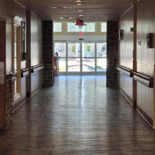 A bright and spacious hallway with wooden flooring leading to an exit.