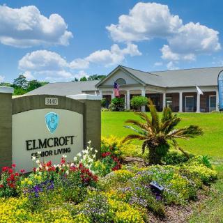 A well-landscaped residential building with a prominent sign and a bright blue sky.