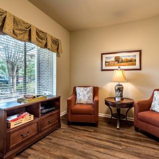 A cozy living room seating area with two armchairs and a small table under warm lighting.
