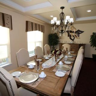 An elegantly set dining room with a long table, complete with stylish tableware and a chandelier.
