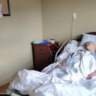An elderly patient resting in a hospital bed surrounded by medical equipment.