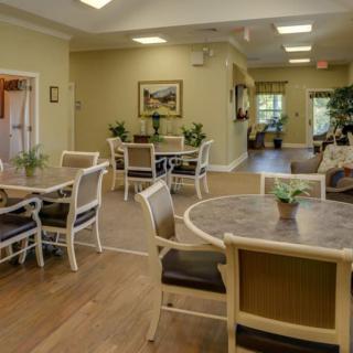 A cozy dining area with tables and chairs, decorated with plants and artwork.