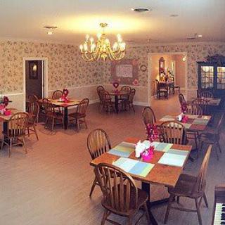 A cozy dining room with wooden tables and chairs, set under a chandelier.