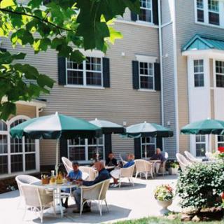 A sunny outdoor patio area with tables, chairs, and umbrellas next to a building.