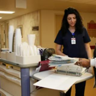 A nurse sorting through documents on a medical cart in a hospital.