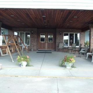 A covered entrance with a swing, chairs, and planters on a concrete porch.