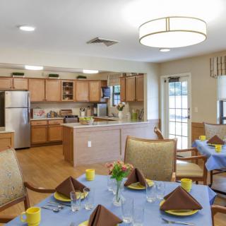 A cozy kitchen and dining area with neatly set tables and wooden cabinetry.
