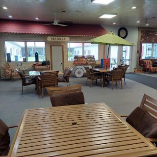 A spacious lounge area featuring wooden furniture and ample seating, designed for relaxation and socializing.