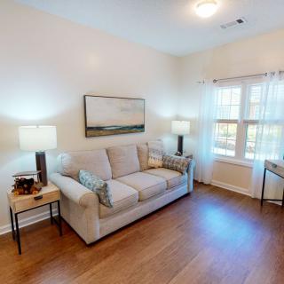 A cozy living room with a comfortable sofa, two lamps, and artwork on the wall.