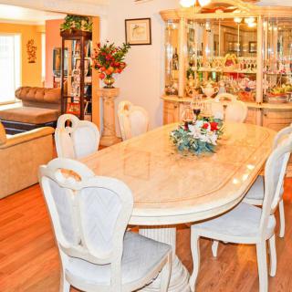 A well-decorated dining room featuring a large table with elegant chairs and a floral centerpiece.