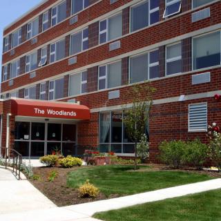 A brick apartment building with a canopy entrance and well-maintained landscaping.