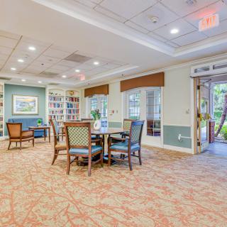 A cozy lounge area with chairs and tables, surrounded by bookshelves and bright lighting.