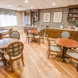 A cozy dining area with wooden tables and chairs, featuring natural lighting and decorative elements.