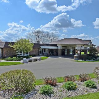 A well-maintained entrance to a modern building, surrounded by lush greenery and under a bright sky.