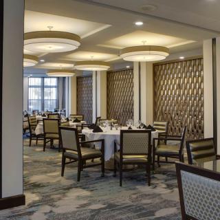 An elegant dining room with neatly arranged tables and chairs, featuring sophisticated interior design and ambient lighting.