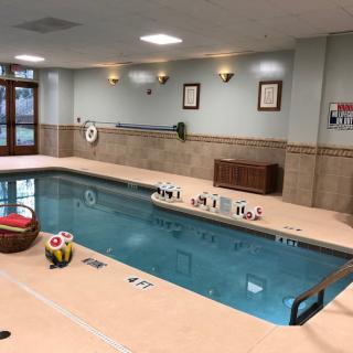 An indoor swimming pool at a hotel with toys and seating areas.