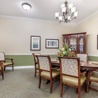 A well-decorated dining room with a large table and elegant chairs beneath a classic chandelier.