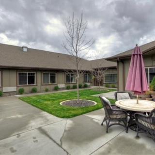 A view of a courtyard with a patio set under an umbrella and a small lawn area on an overcast day.