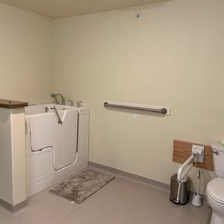 An accessible bathroom with a walk-in tub, grab bar, and toilet.