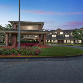 A residential building with a well-lit entrance and landscaped surroundings at sunset.