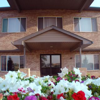 A brick house with colorful flowers in the foreground.