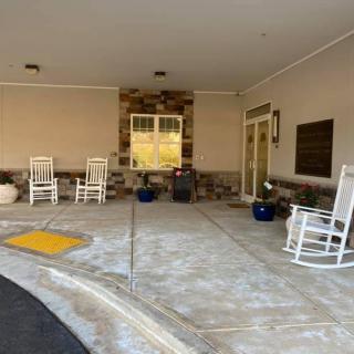 A welcoming porch with rocking chairs and potted plants at a building entrance.
