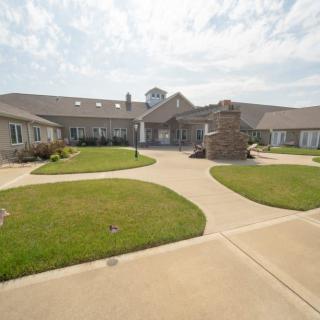 A view of a modern building with well-maintained lawns and pathways under a partly cloudy sky.