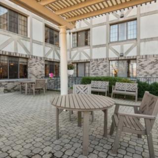 A cozy outdoor patio area with wooden furniture and a pergola overhead.