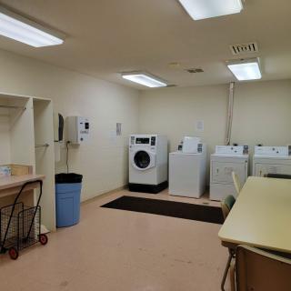 A clean and organized laundry room with washing machines, dryers, and a folding table.