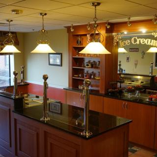 A cozy ice cream parlor with a polished wooden counter and elegant pendant lighting.