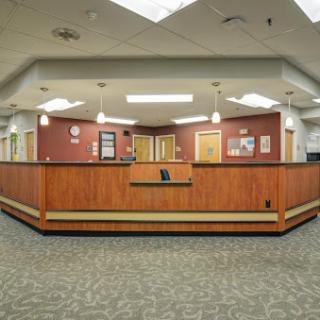 A spacious reception area in a hospital, featuring a wooden front desk and comfortable waiting space.