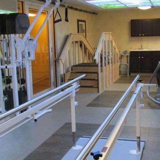 A physical therapy room equipped with parallel bars and rehabilitation equipment.